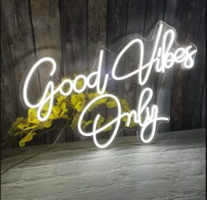 Décoration murale lumineuse "Good vibes only" blanche sur un mur en bois